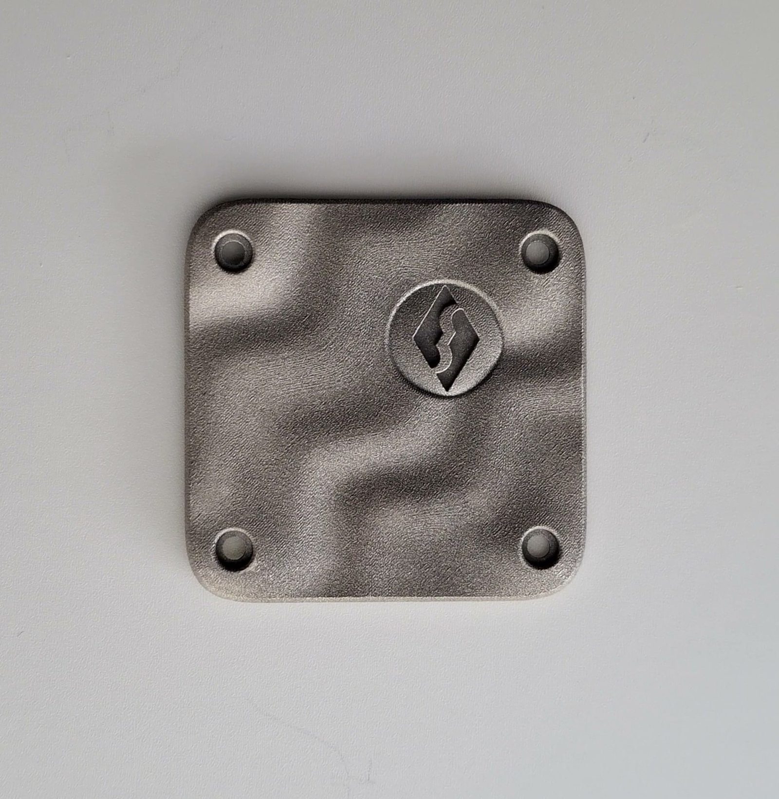 The caseback plate, cast and blasted, the mark raised at the centre